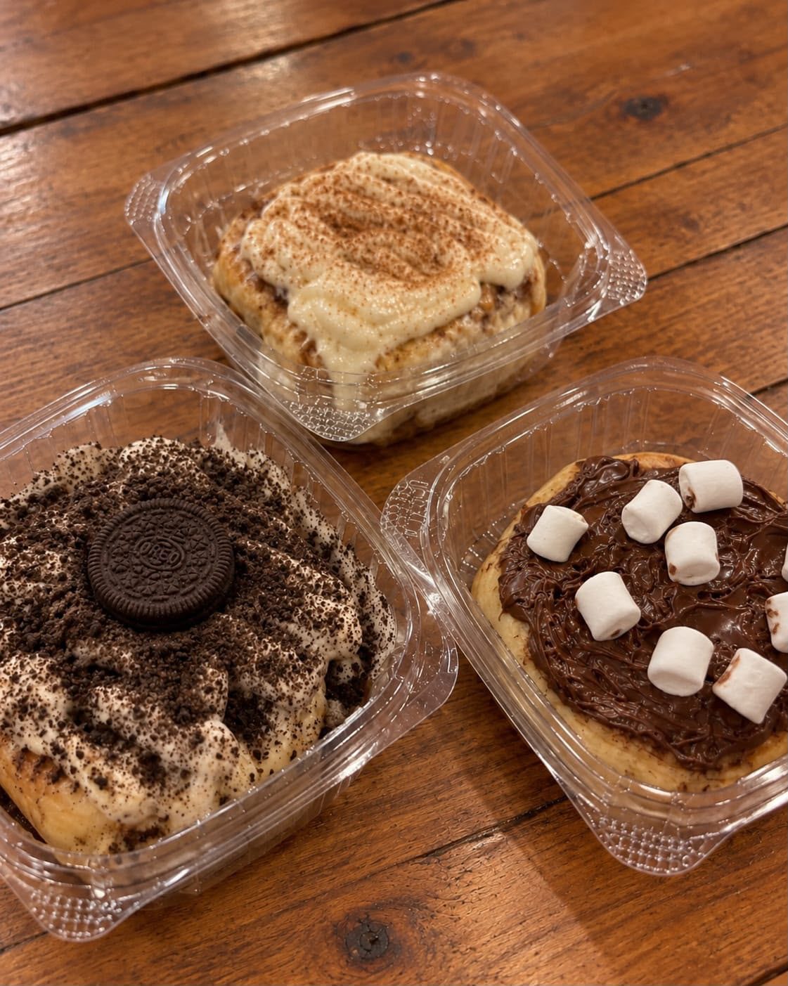 Tres Golden Rolls: canela & crema, Oreo y Nutella & Marshmallow sobre mesa de madera